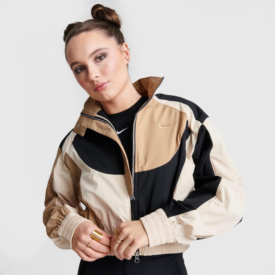 WOMEN'S NIKE SPORTSWEAR COLLECTION JACKET in a sand colored with a woman modeling it on a grey background.