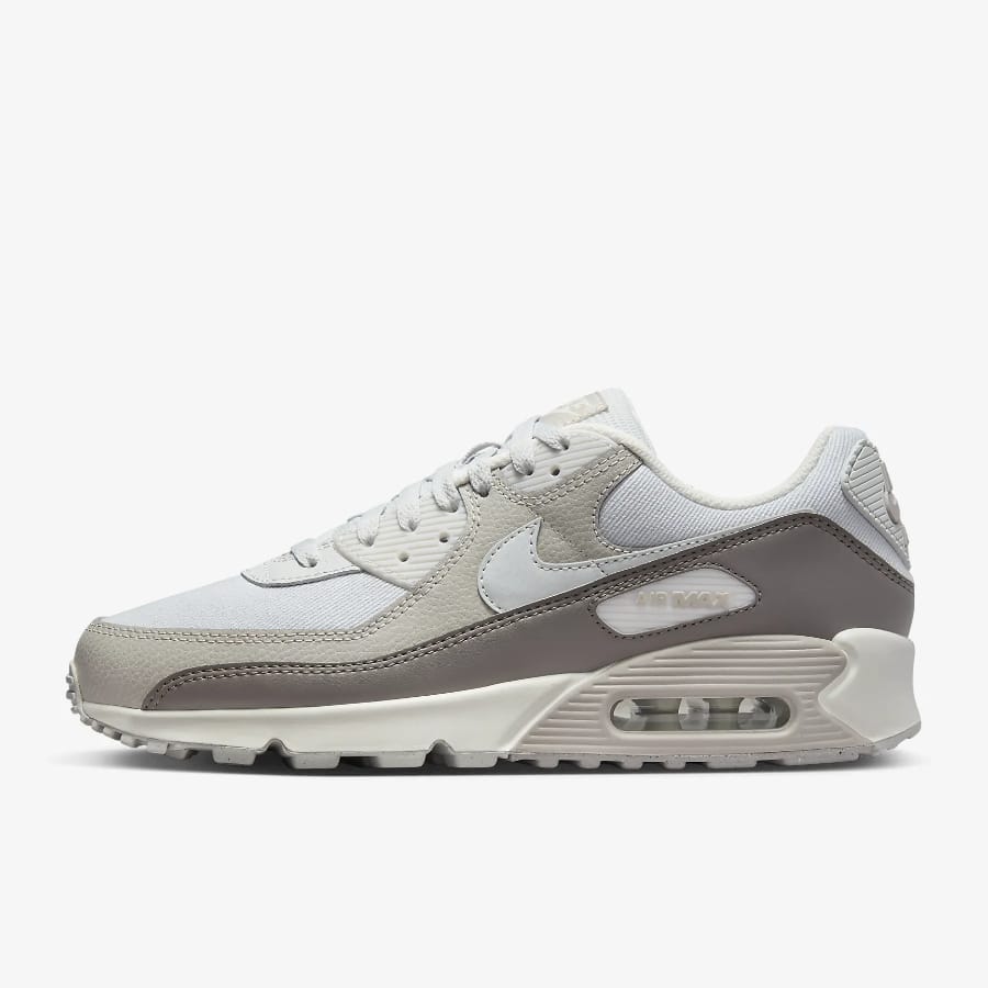 Nike Air Max 90 - Photon Dust/Light Iron Ore/Sail/Photon Dust colorway on a light gray background. 