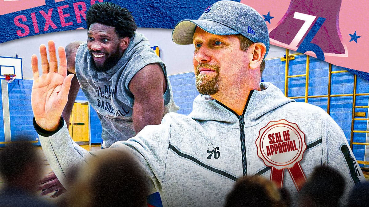 Sixers center Joel Embiid standing behind Nick Nurse, who is wearing a big ribbon