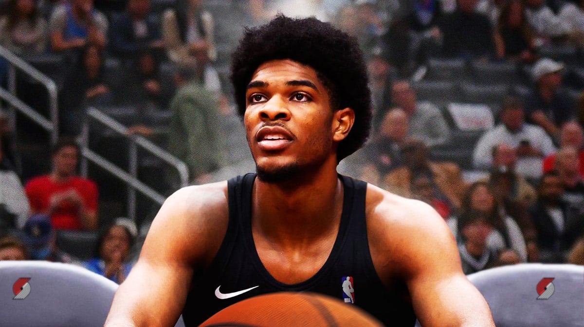 Blazers' Scoot Henderson sitting down on an NBA sideline looking serious.