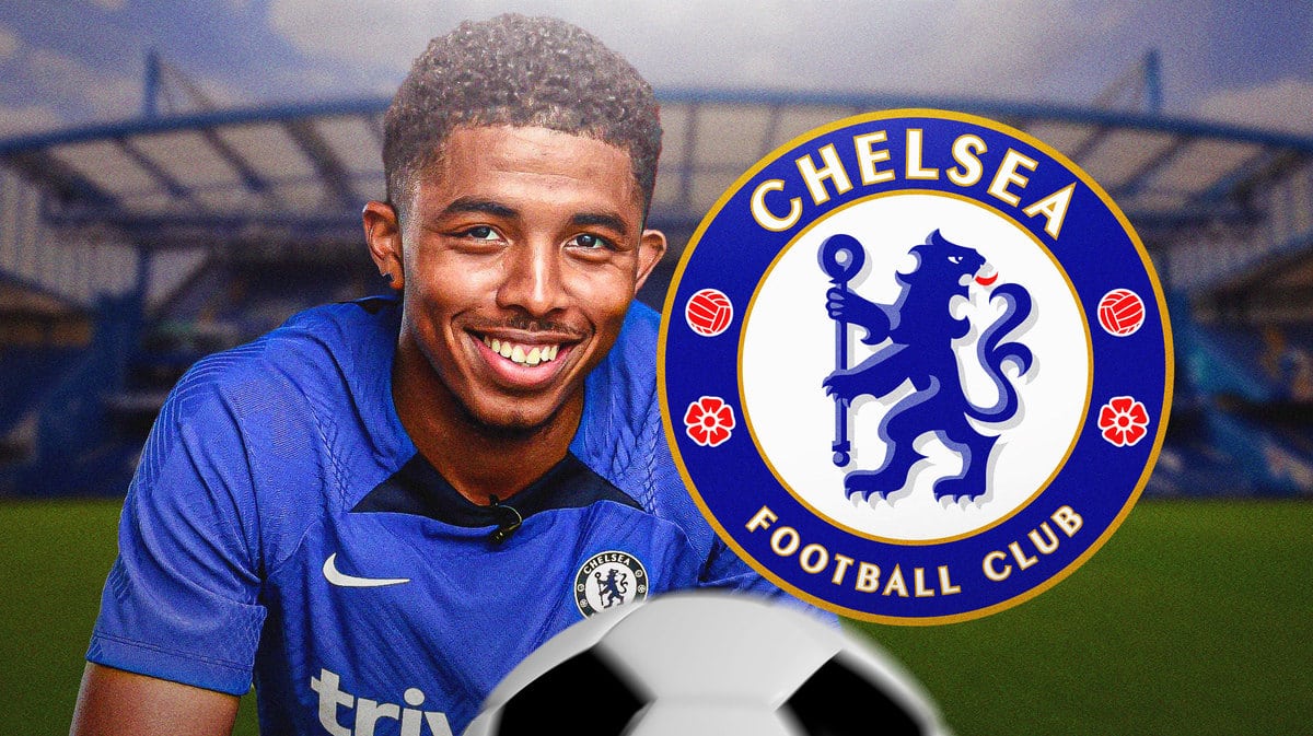 Wesley Fofana smiling in front of the Chelsea logo