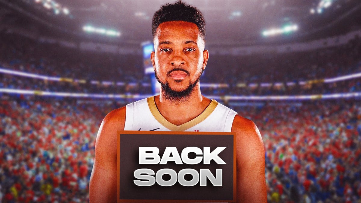 CJ McCollum smiling, while holding the BACK SOON sign