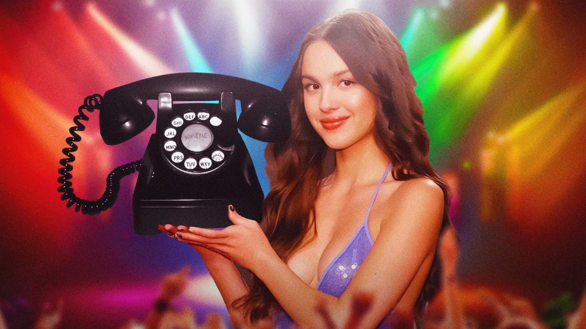Olivia Rodrigo holding a telephone (hotline) in front of stage.