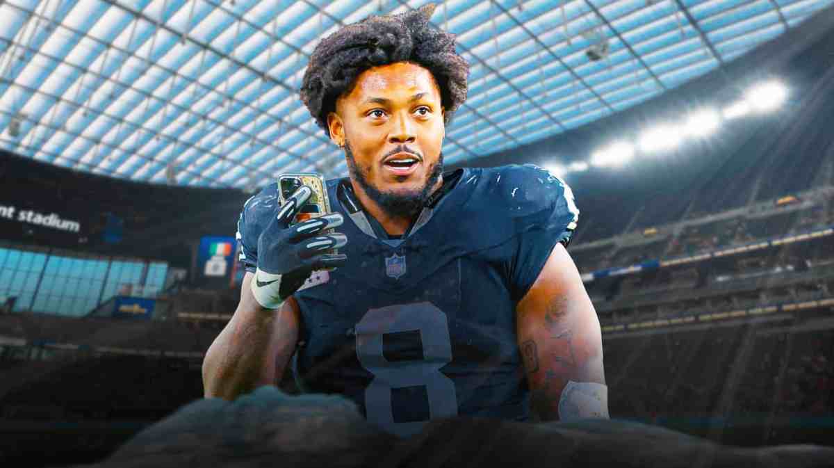 Las Vegas Raiders running back Josh Jacobs in the foreground holding a phone and looking surprised.