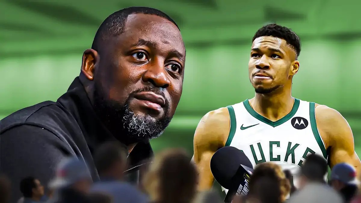 Bucks head coach Adrian Griffin in front of a microphone with Giannis Antetokounmpo at the back