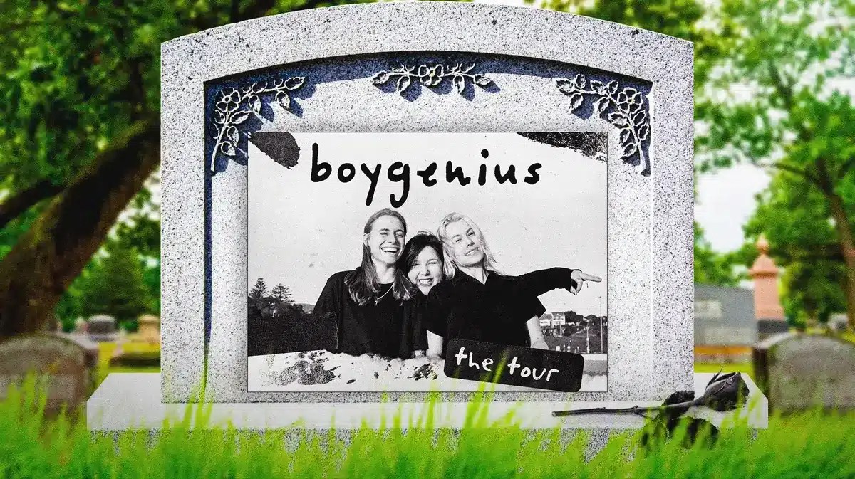 The members of the band boygenius smiling on a gravestone