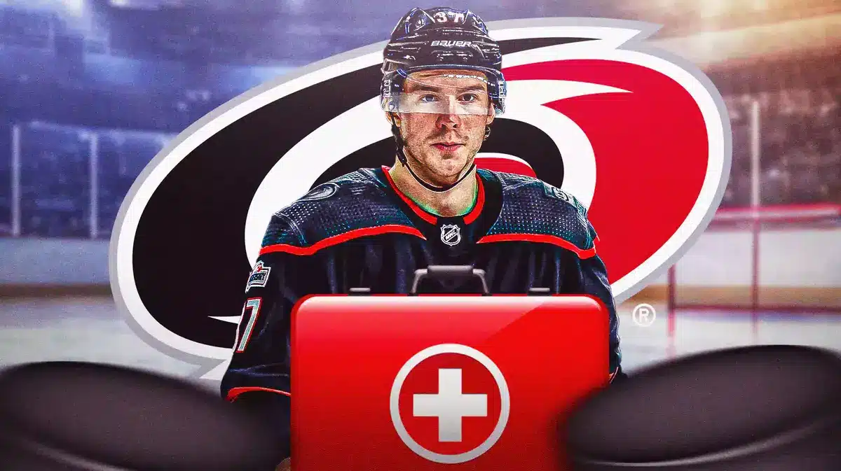 Andrei Svechnikov in middle of image looking stern, first aid kit, CAR Hurricanes logo in image, hockey rink in background