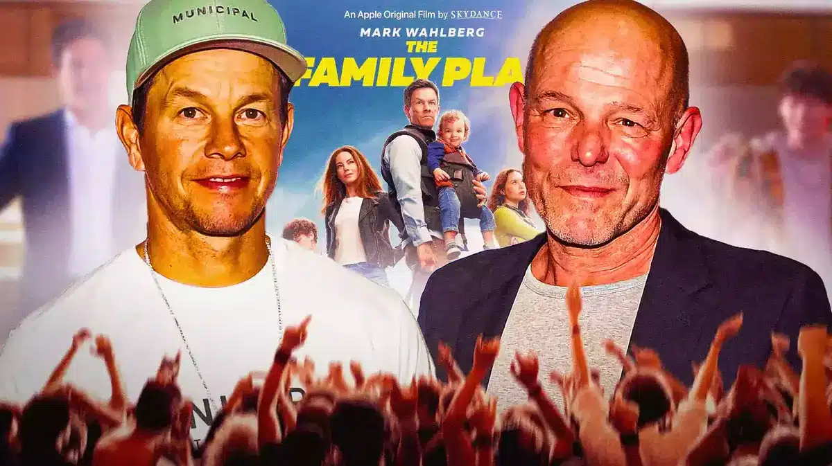 Mark Wahlberg and Simon Cellan Jones between The Family Plan poster.