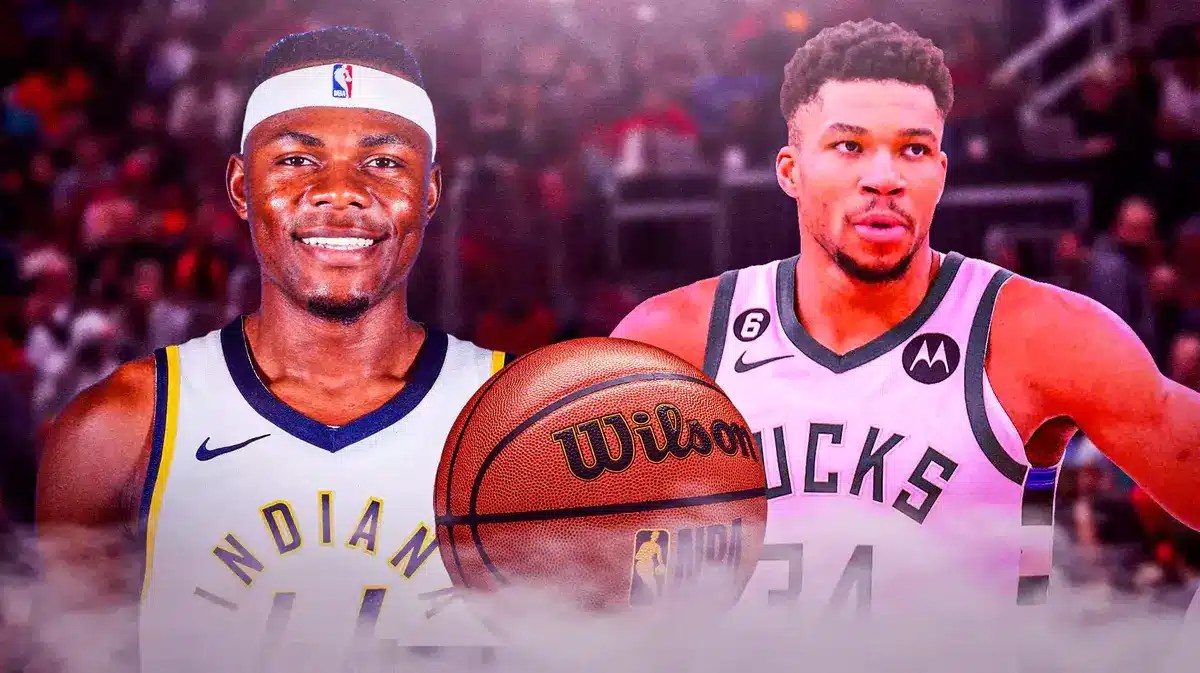 Pacers' Oscar Tshiebwe smiling, with Bucks' Giannis Antetokounmpo looking serious beside him, with an official Wilson NBA game ball in the middle