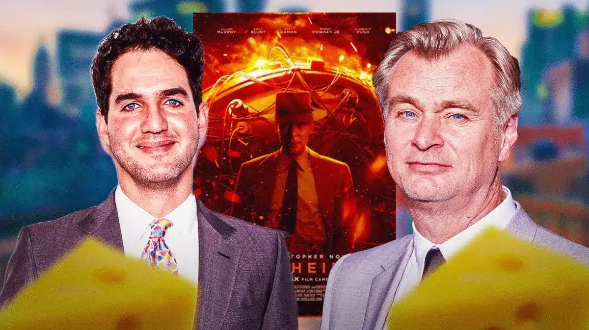 Benny Safdie and Christopher Nolan between Oppenheimer poster.