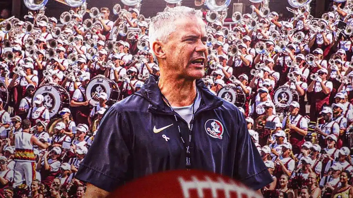 Photo: Mike Norvell with FSU gear smiling and FSU fans in the back
