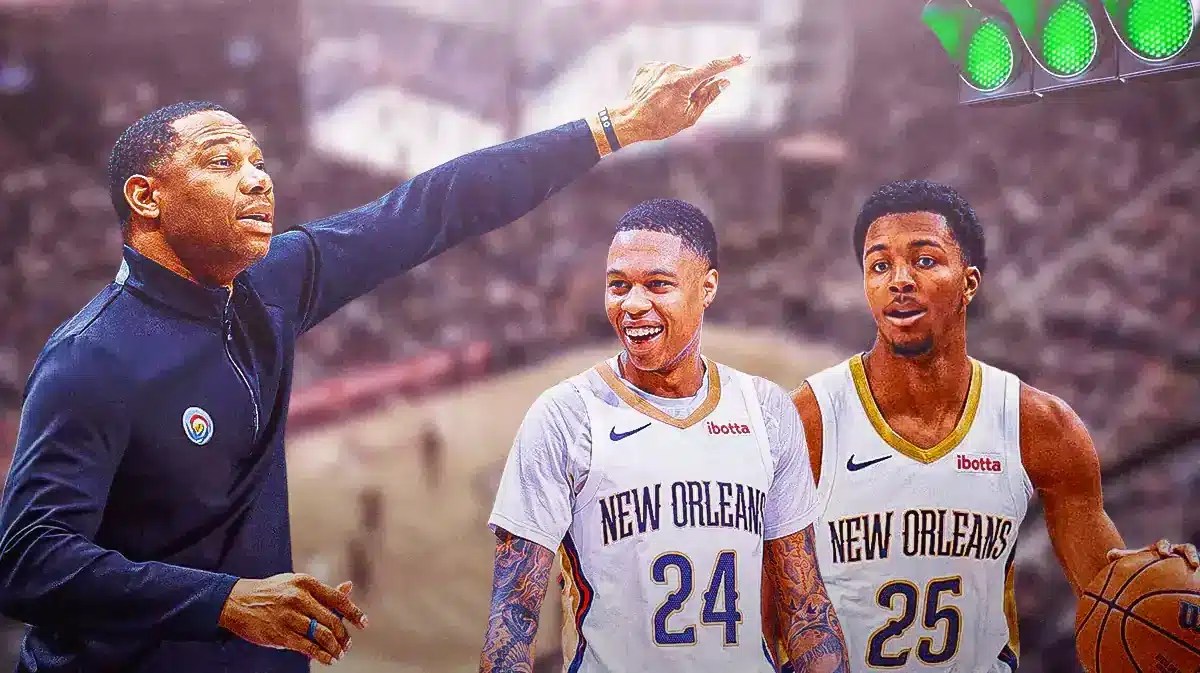 Pelicans coach Willie Green, pointing at a green light with Jordan Hawkins and Trey Murphy III under it.