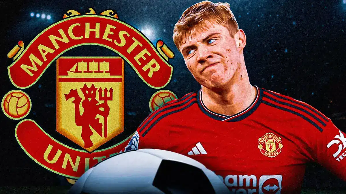 Rasmus Hojlund looing down/sad in front of the Manchester United logo