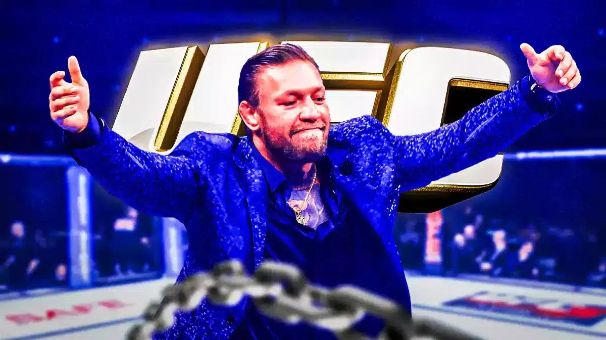 Conor McGregor laughing in the UFC cage in front of the UFC logo