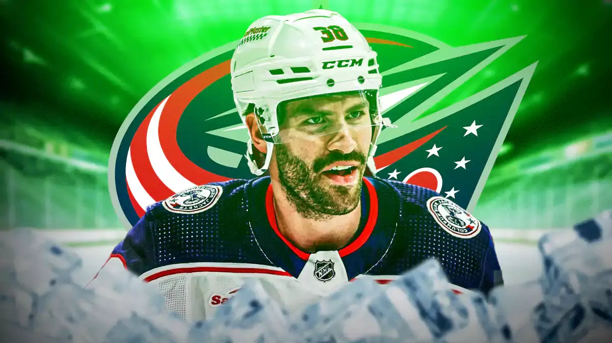 Boone Jenner in middle of image, green light in image, Columbus Blue Jackets logo, hockey rink in background