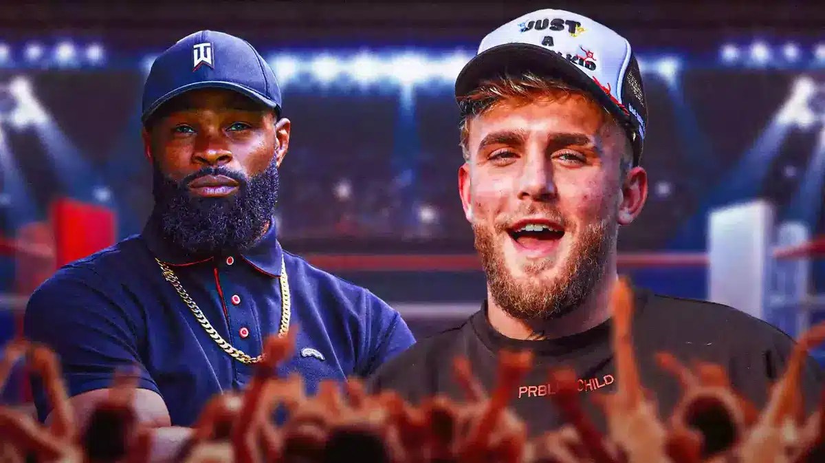 Tyron Woodley looking down/sad, Jake Paul laughing next to him, a boxing ring behind them