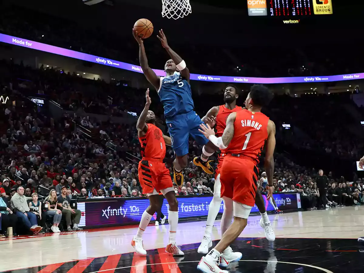 Minnesota Timberwolves guard Anthony Edwards (5) shoots the ball over Portland Trail Blazers forward Jerami Grant (9), center Deandre Ayton (2), and guard Anfernee Simons (1) in the second quarter at Moda Center.
