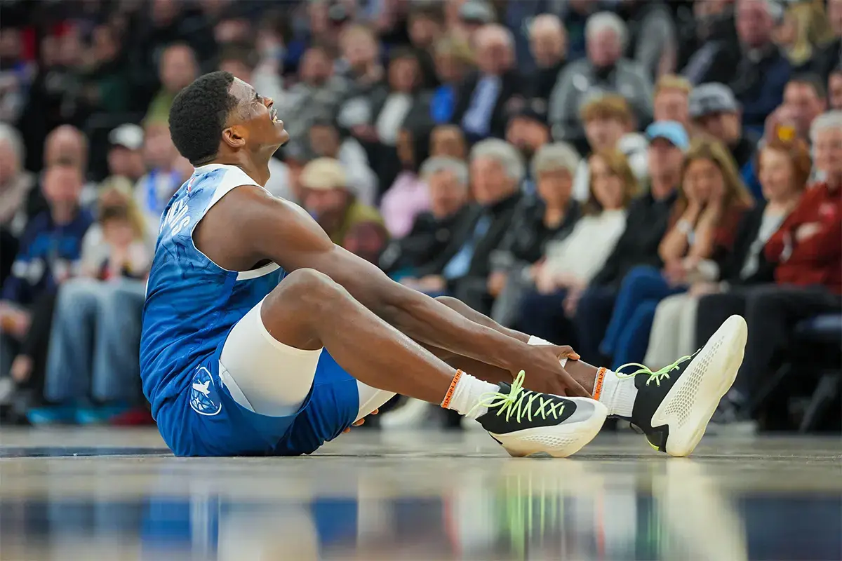 Minnesota Timberwolves guard Anthony Edwards (5) holds his ankle on the ground against the San Antonio Spurs in the second quarter at Target Center.