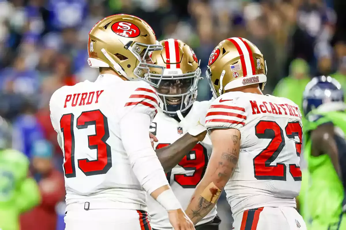 San Francisco 49ers running back Christian McCaffrey (23) celebrates with quarterback Brock Purdy (13) and wide receiver Deebo Samuel (19) after catching a touchdown pass from Purdy against the Seattle Seahawks during the second quarter at Lumen Field.