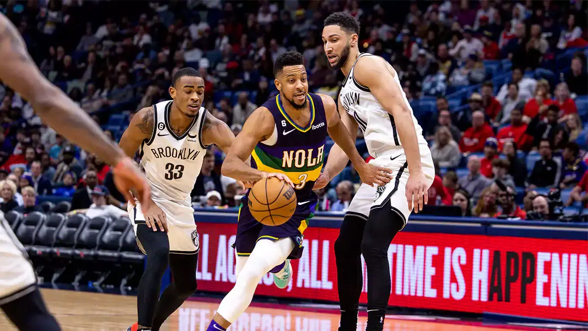 New Orleans Pelicans guard CJ McCollum (3) dribbles against Brooklyn Nets center Nic Claxton (33) and guard Ben Simmons (10) during the second half at Smoothie King Center. 
