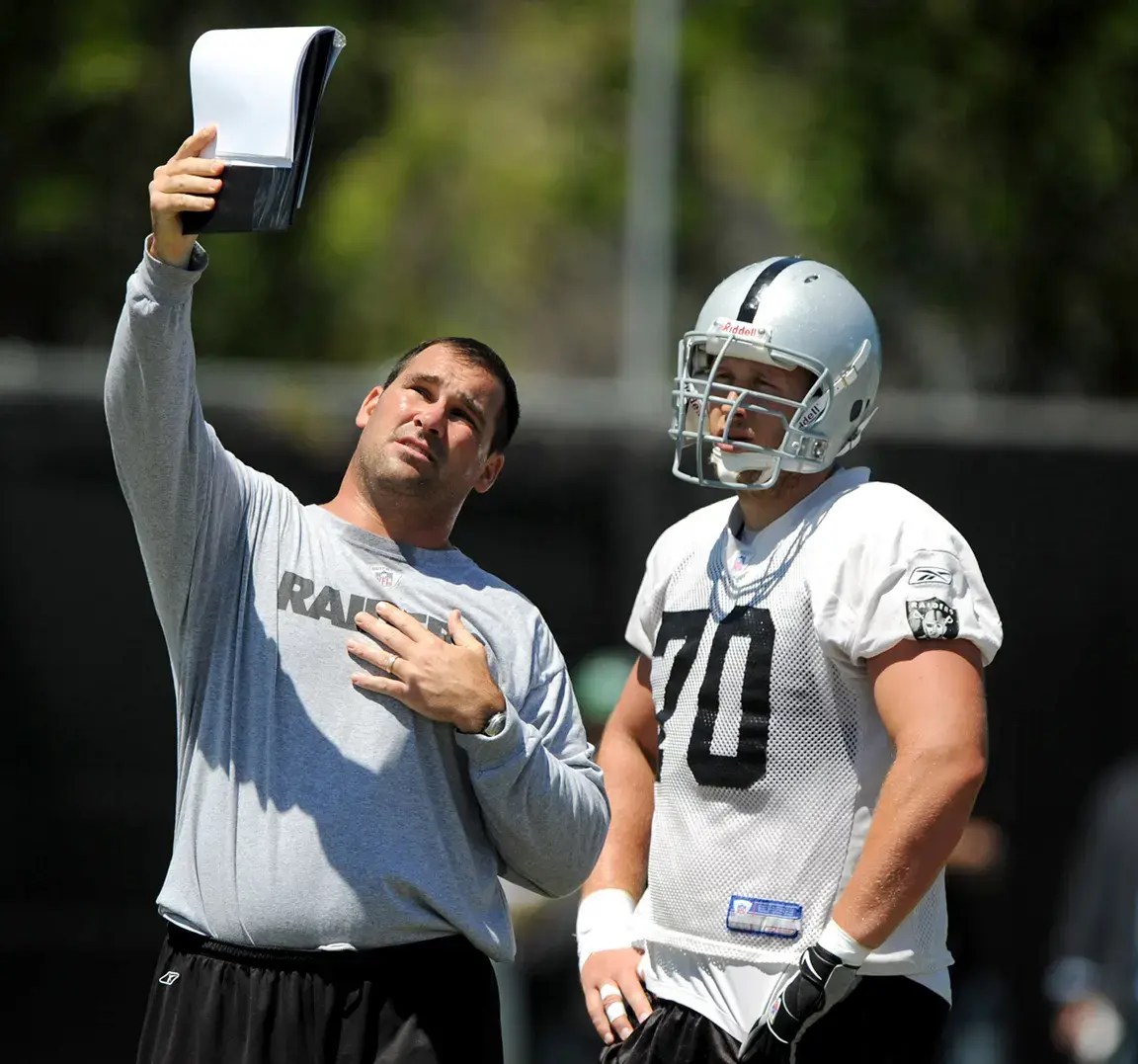 Oakland Raiders assistant offensive line coach James Cregg displays a formation to center Jesse Boone (70) during minicamp at the Raiders practice facility.