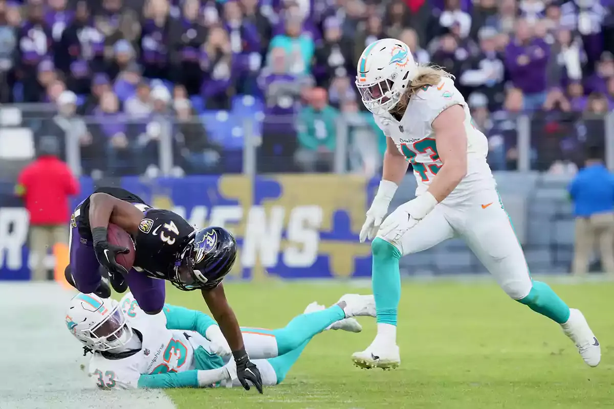 Baltimore Ravens tight end Isaiah Likely (43) runs for a second quarter gain defended by Miami Dolphins cornerback Eli Apple (33) and linebacker Andrew Van Ginkel (43) at M&T Bank Stadium.