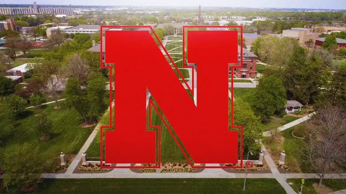 the University of Nebraska logo with the University of Nebraska campus in the background. Ashley Scoggin played basketball for Nebraska.