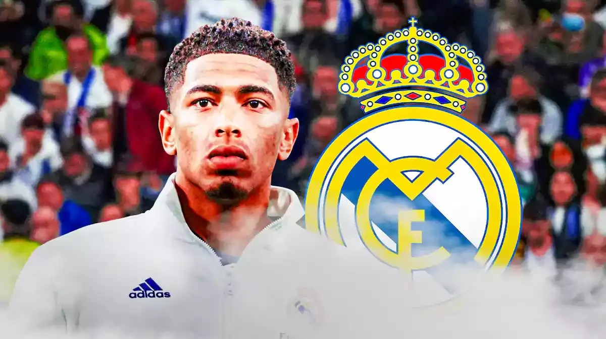 Jude Bellingham looking down in front of the Real Madrid logo