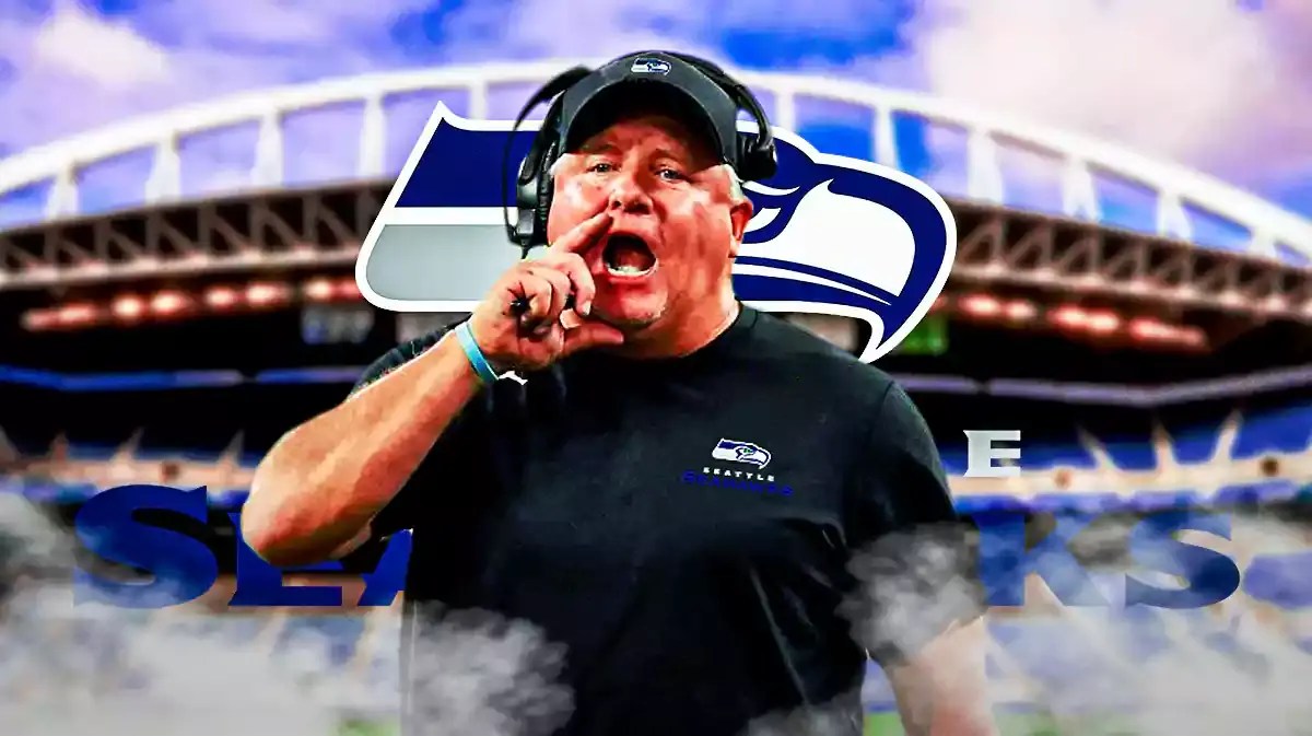 Chip Kelly wearing Seahawks gear in front of a Seahawks logo at Lumen Field