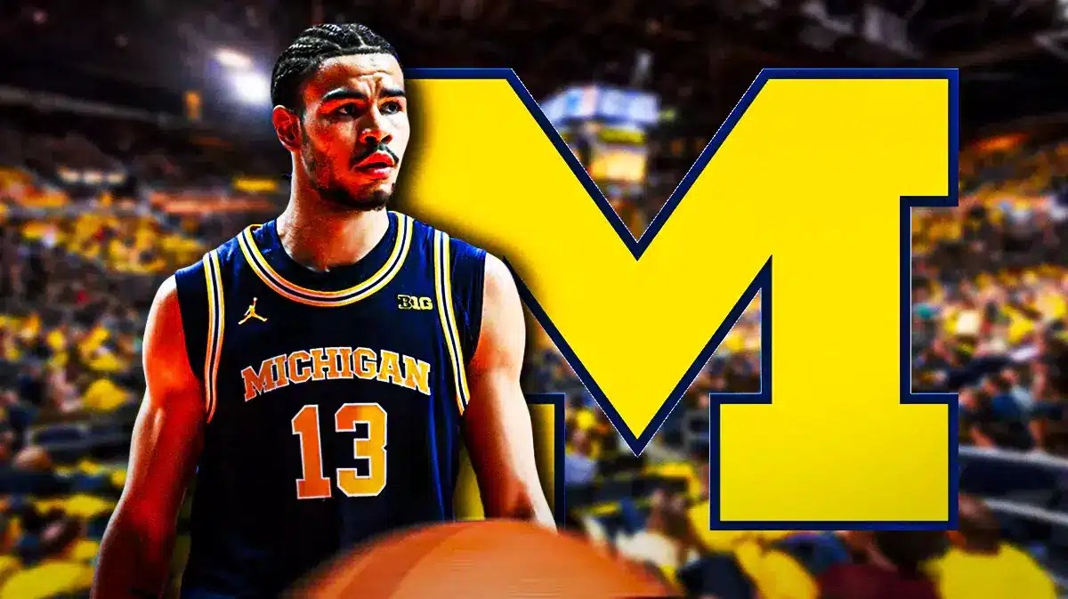 Olivier Nkamhoua next to a Michigan logo at Crisler Center