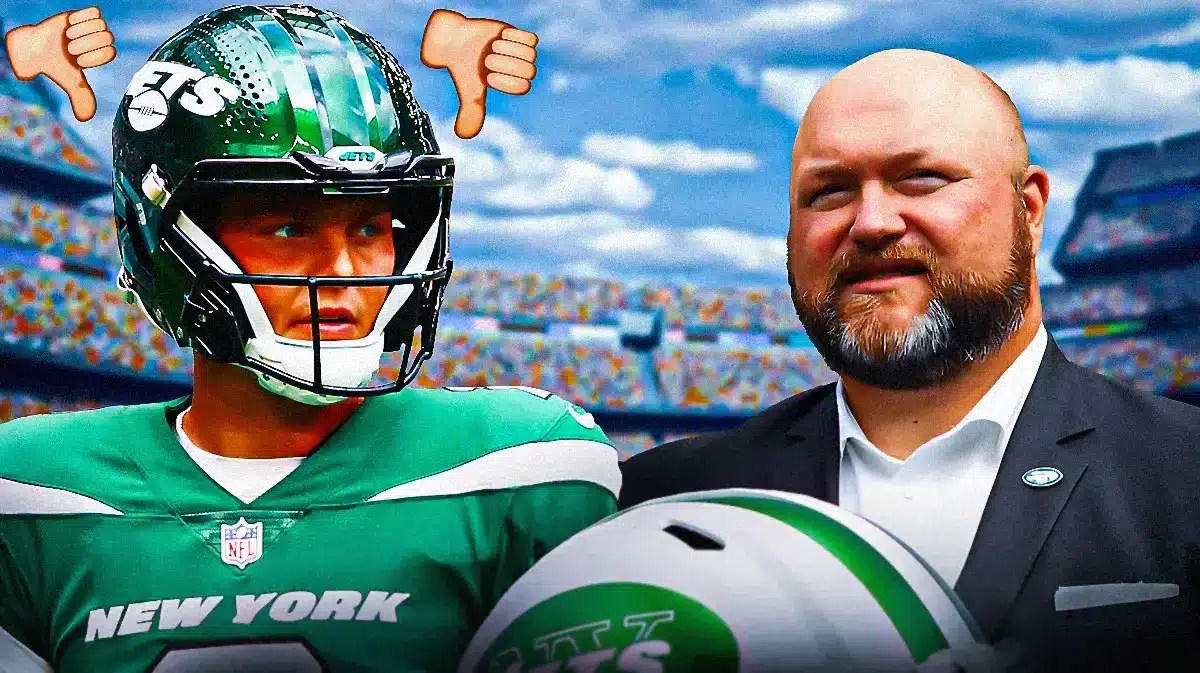 Zach Wilson with several thumbs pointing down above his head. Looking on is Jets GM Joe Douglas