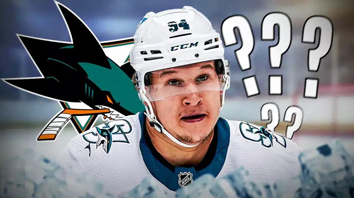 Alexander Barabanov in middle of image looking stern, 3-5 question marks in image, SJ Sharks logo, hockey rink in background