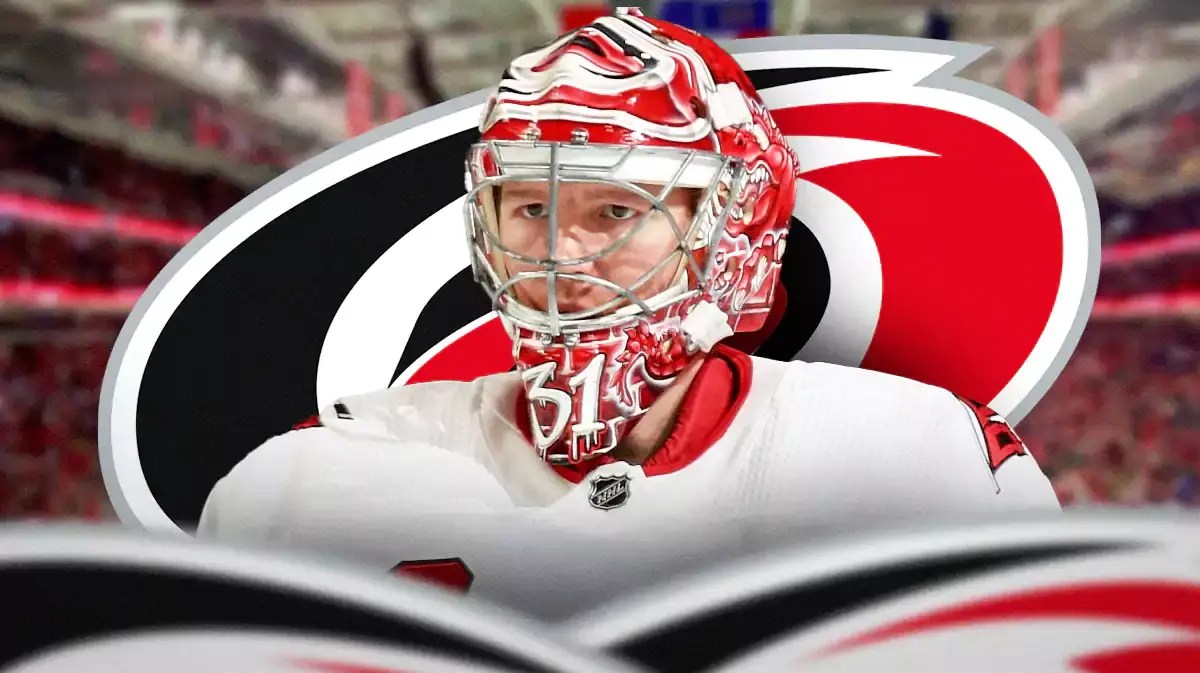 Frederik Andersen in middle of image looking hopeful, CAR Hurricanes logo, hockey rink in background