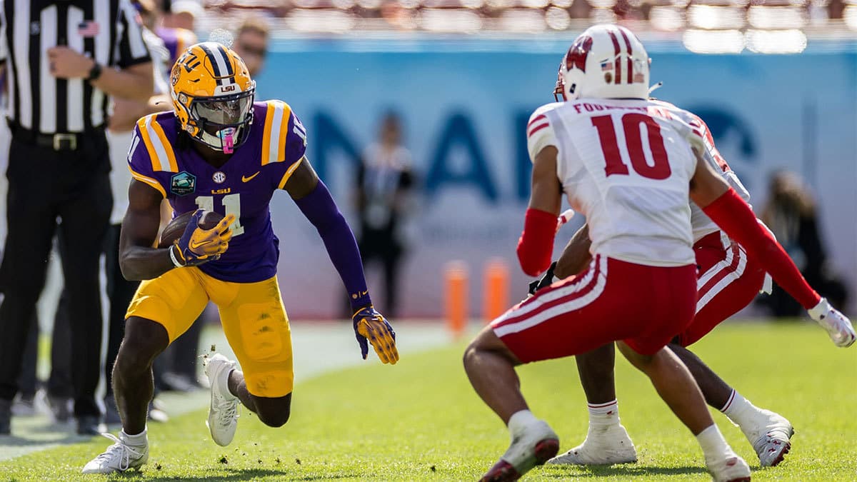 LSU Tigers wide receiver Brian Thomas Jr. (11) runs with the ball towards Wisconsin Badgers cornerback Nyzier Fourqurean (10) during the first half at Raymond James Stadium