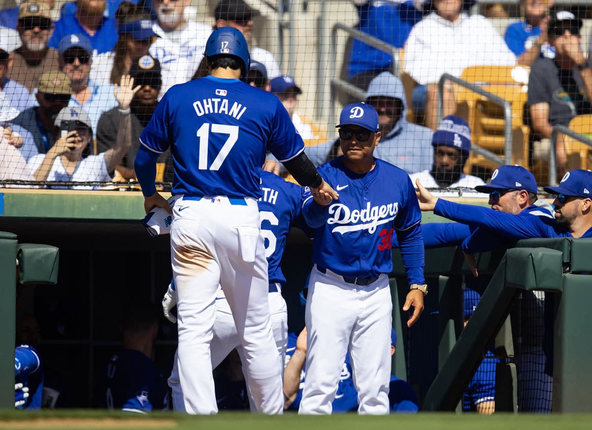 Los Angeles Dodgers designated hitter Shohei Ohtani (17) celebrates with manager Dave Roberts after scoring against the Colorado Rockies during a spring training game at Camelback Ranch-Glendale.