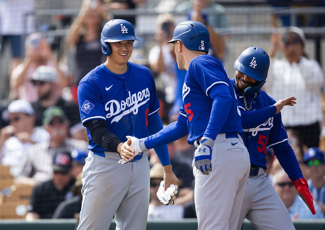 Los Angeles Dodgers designated hitter Shohei Ohtani (left) and Mookie Betts (right) celebrates with first baseman Freddie Freeman after hitting a grand slam home run against the Chicago White Sox during a spring training baseball game at Camelback Ranch-Glendale.