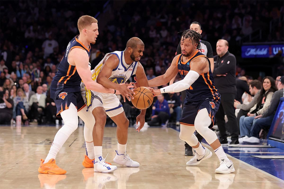 Golden State Warriors guard Chris Paul (3) fights for the ball against New York Knicks guards Donte DiVincenzo (0) and Jalen Brunson (11) during the fourth quarter at Madison Square Garden. 