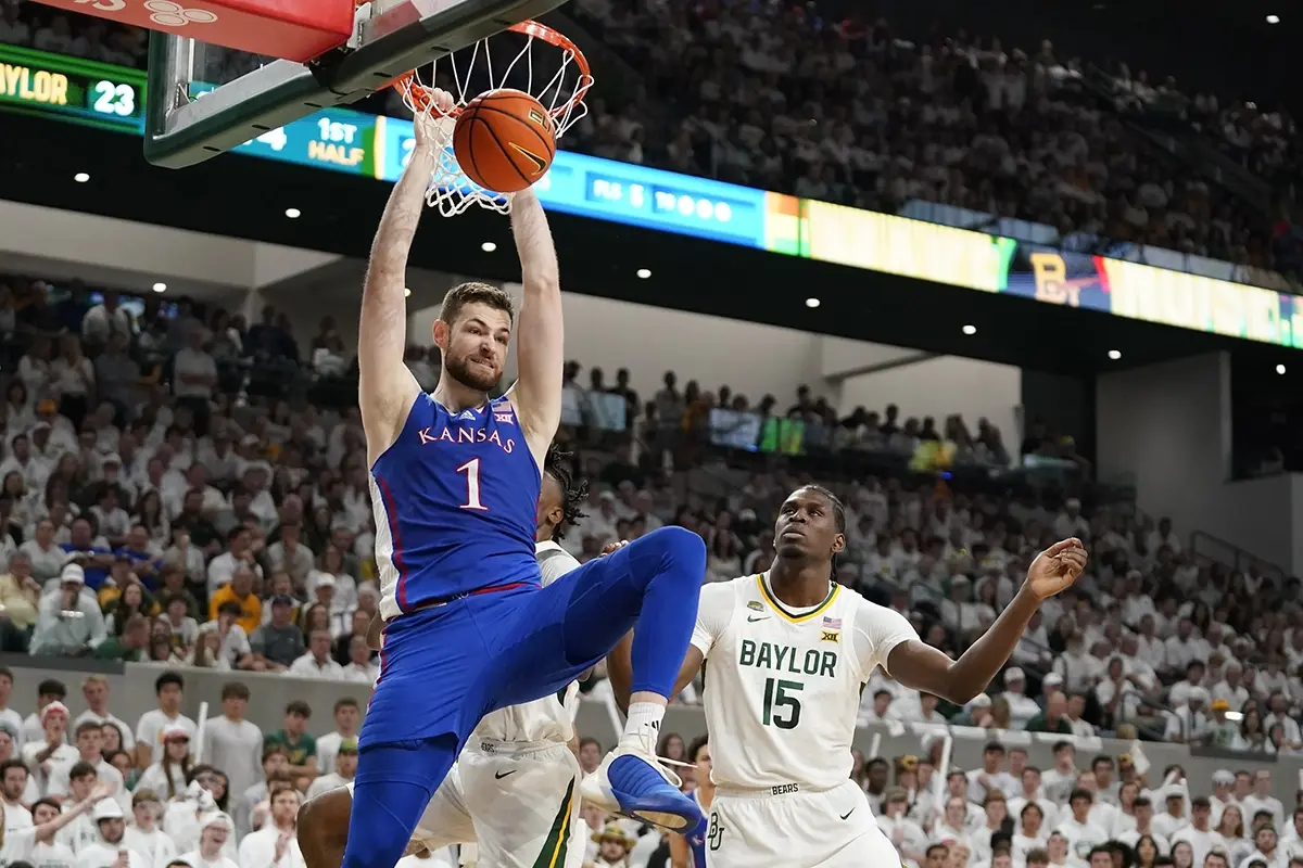 Kansas Jayhawks center Hunter Dickinson (1) hangs on the rim after a dunk in front of Baylor Bears forward Josh Ojianwuna (15) during the first half at Paul and Alejandra Foster Pavilion