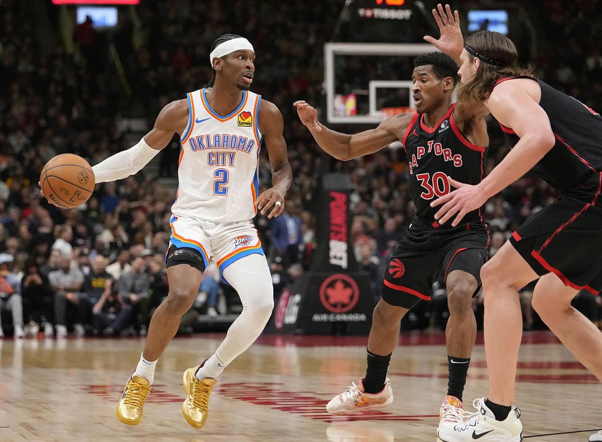 Oklahoma City Thunder guard Shai Gilgeous-Alexander (2) looks to make a play against Toronto Raptors guard Ochai Agbaji (30) and forward Kelly Olynyk (41) during the first half at Scotiabank Arena.