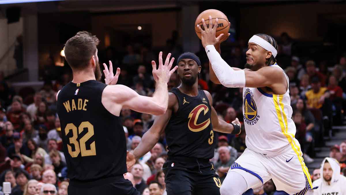 Golden State Warriors guard Moses Moody (4) makes a pass between Cleveland Cavaliers guard Caris LeVert (3) and forward Dean Wade (32) in the third quarter at Rocket Mortgage FieldHouse