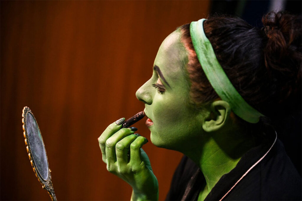 Elphaba putting on makeup for the play Wicked