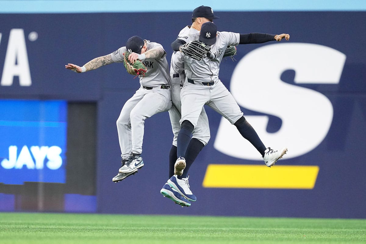 New York Yankees left fielder Alex Verdugo (24), center fielder Aaron Judge (99) and right fielder Juan Soto (22) celebrate the win against the Toronto Blue Jays at the end of the ninth inning at Rogers Centre.