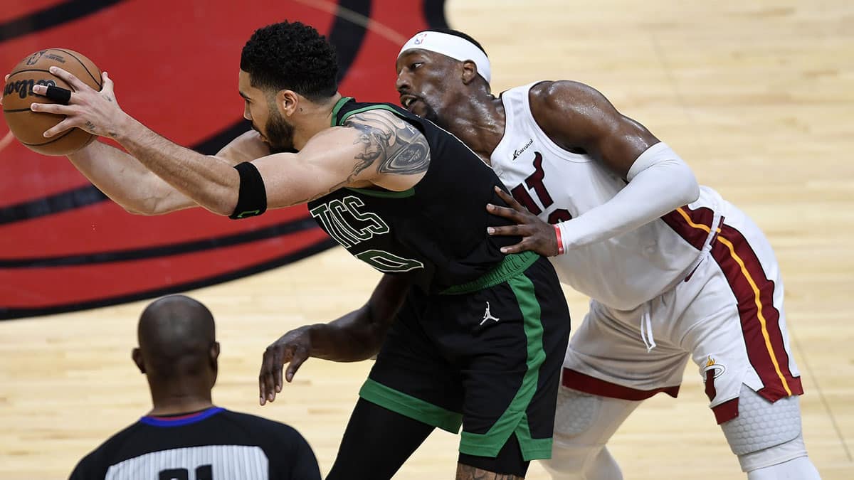 Boston Celtics forward Jayson Tatum (0) keeps the ball away from Miami Heat center Bam Adebayo (13) during the fourth quarter of game four of the first round for the 2024 NBA playoffs at Kaseya Center. 