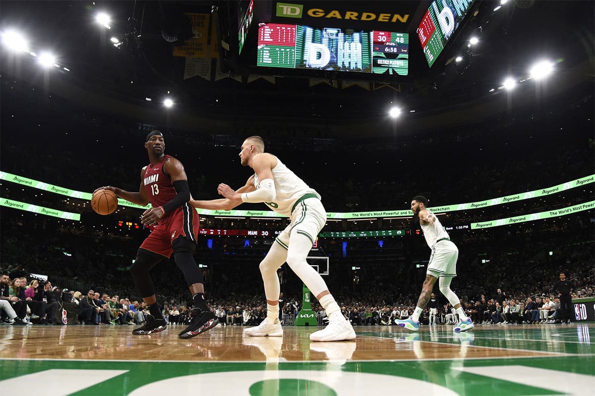 Miami Heat center Bam Adebayo (13) controls the ball while Boston Celtics center Kristaps Porzingis (8) defends during the first half in game one of the first round for the 2024 NBA playoffs at TD Garden.
