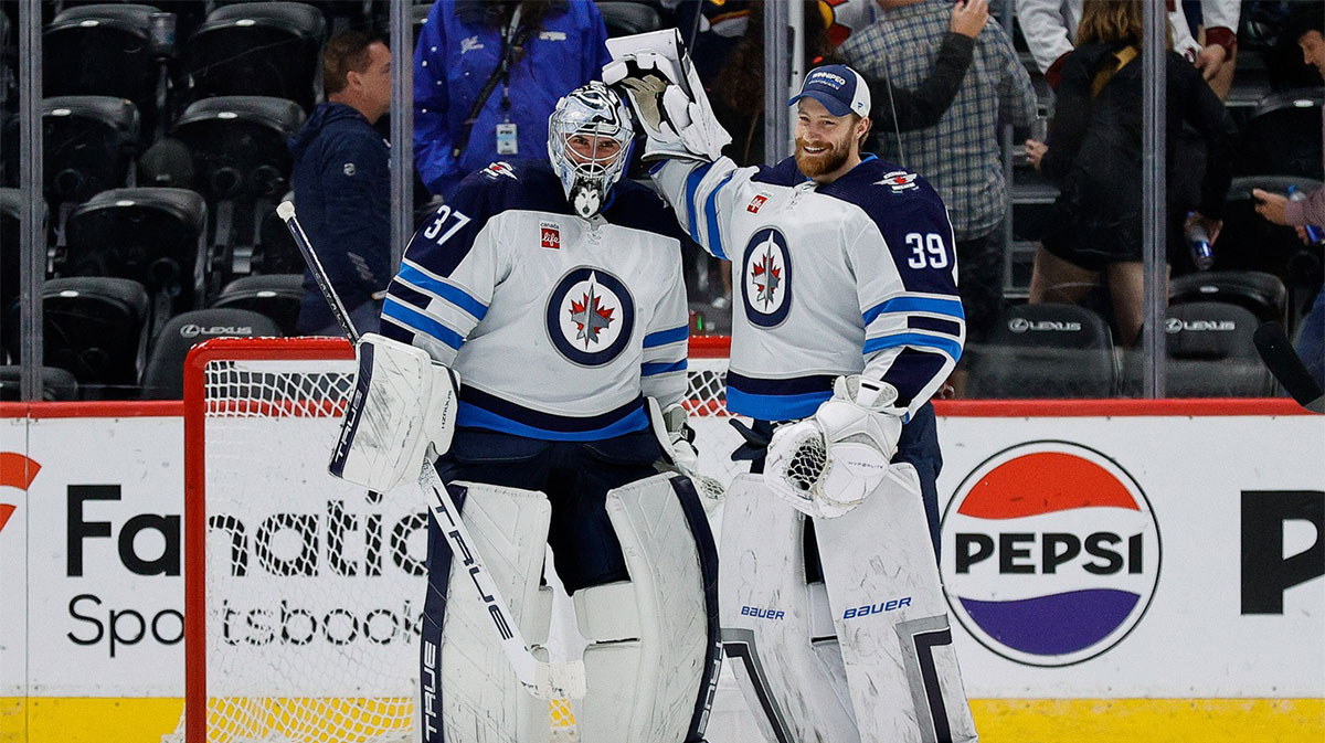 Winnipeg Jets goaltender Connor Hellebuyck (37) reacts with goaltender Laurent Brossoit (39) after the game against the Colorado Avalanche at Ball Arena