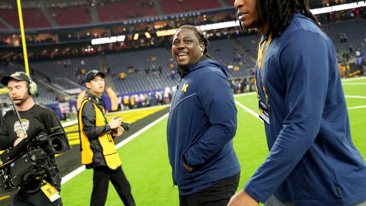 Former Michigan quarterback Denard Robinson, center, smiles at someone in the stands as he walks in with the Michigan football team before the start of the College Football Playoff national championship game at NRG Stadium in Houston on Monday, Jan. 8, 2024.