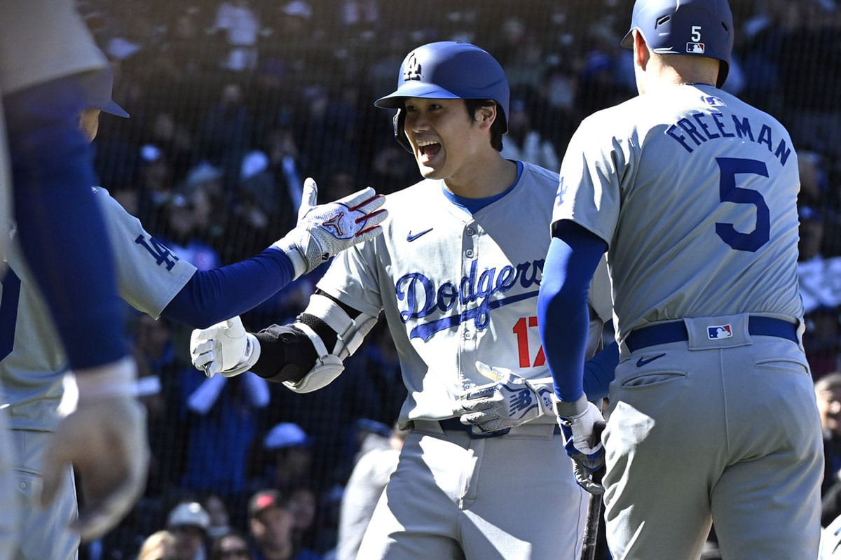  Los Angeles Dodgers two-way player Shohei Ohtani (17) high fives shortstop Mookie Betts (left) after hitting a two-run home run against the Chicago Cubs as first baseman Freddie Freeman (5) looks on during the fifth inning at Wrigley Field