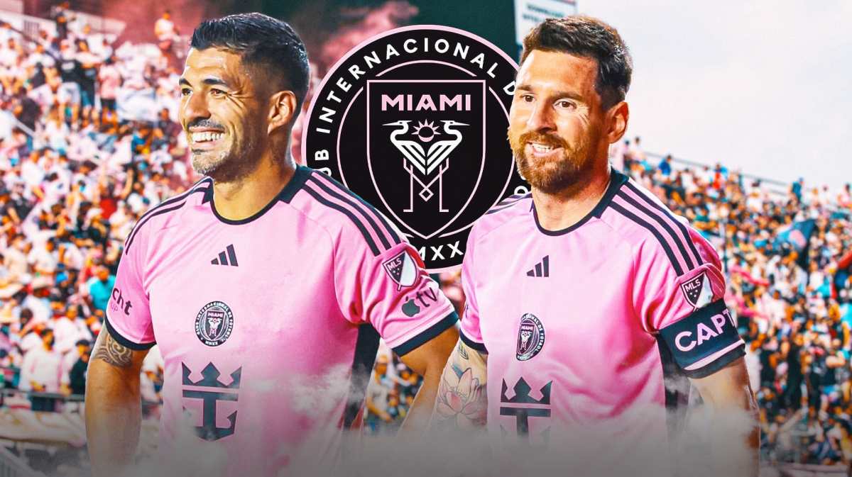 Lionel Messi and Luis Suarez smiling towards each other in front of the Inter Miami logo