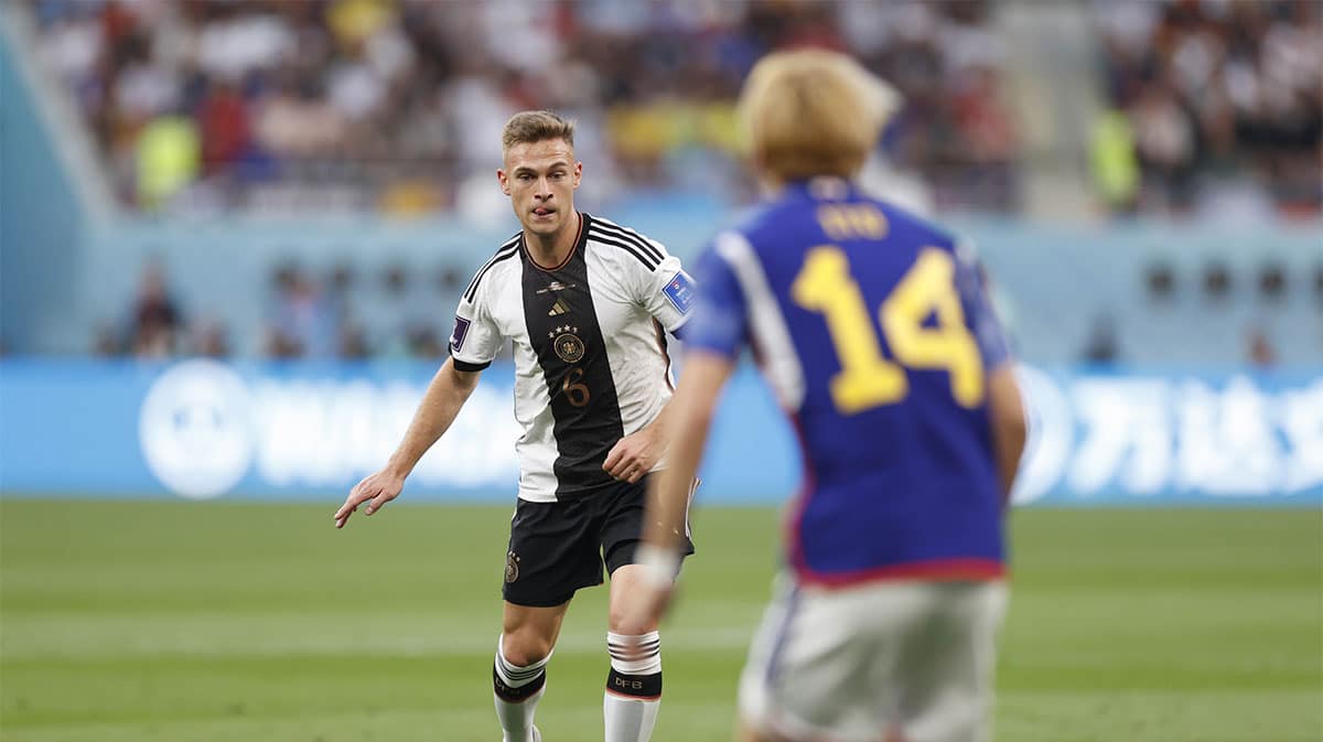 Germany midfielder Joshua Kimmich (6) is defended by Japan forward Junya Ito (14) during a group stage match during the 2022 World Cup at Khalifa International Stadium