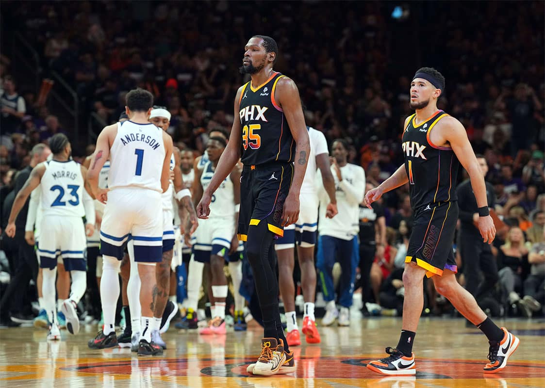 Phoenix Suns forward Kevin Durant (35) and Phoenix Suns guard Devin Booker (1) react while Minnesota Timberwolves players celebrate during the second half of game three of the first round for the 2024 NBA playoffs at Footprint Center. 